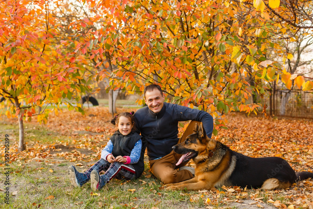 Young family with a dog in leaves on an autumns day