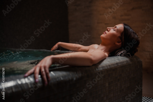 Conception of bodycare. Beauty and body care. View of a young woman enjoying whirlpool bath. Sensual young woman relaxing in spa hot tub.