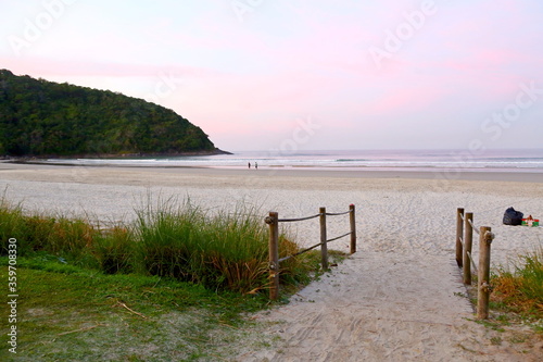 Brazil  Bertioga  Sao Louren  o beach. Beach at dawn with sand and in the background the sea with calm waves. To the left side a mountain and clear sky on the horizon.