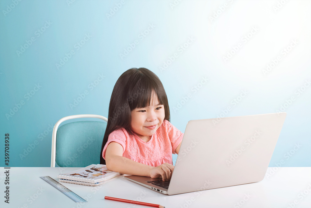 Smart little girl using laptop for doing his homework, isolated on blue background, E-learning and online education concept. Smart little girl using laptop for doing his homework, isolated on blue background, E-learning and online education concept.