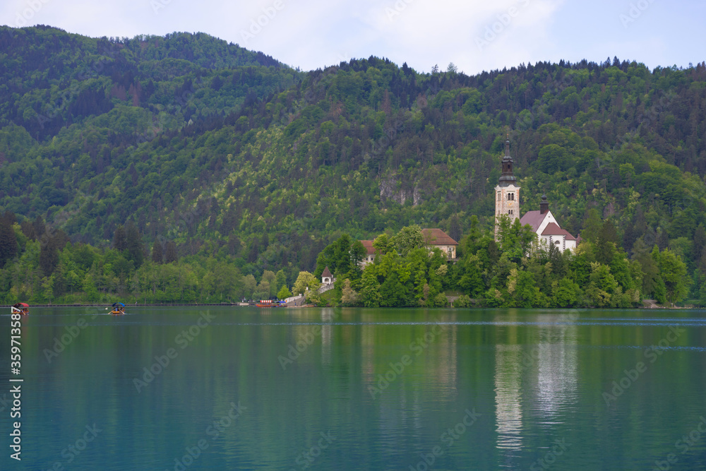 Morning at Lake Bled and Julian Alps in the background. The lake island and charming little church dedicated to the Assumption of Mary are famous tourist attraction in Slovenia