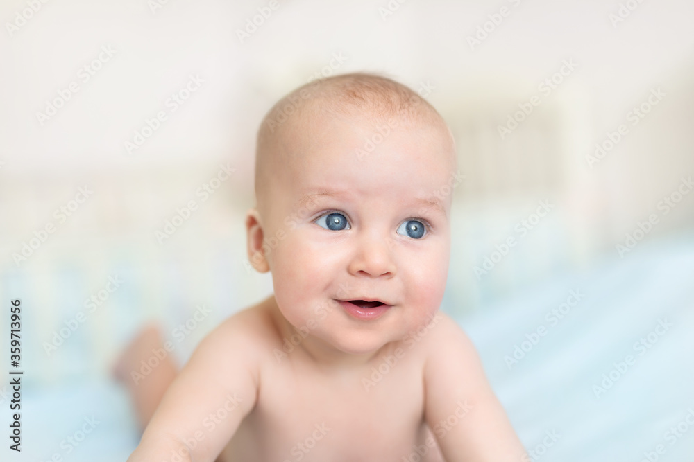 Cute adorable caucasian little 5 month old infant baby boy lying on tummy at nursery bed room having fun playing and smiling. Happy healthy newborn child concept. Funny toddler kid closeup portrait Cute adorable caucasian little 5 month old infant baby boy lying on tummy at nursery bed room having fun playing and smiling. Happy healthy newborn child concept. Funny toddler kid closeup portrait