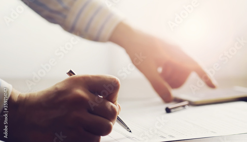 Business meeting. A man signs a contract. Male hand with pen makes notes in the office.