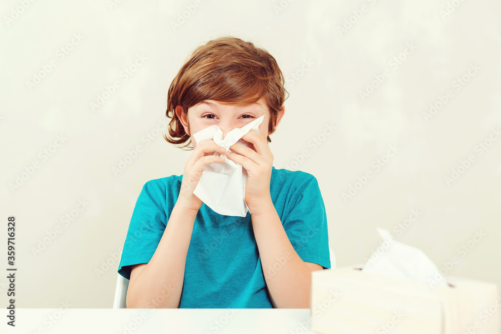Schoolboy blowing runny nose. Sick boy sitting at desk. Kid using paper napkins. Allergic kid, flu season. Schoolboy blowing runny nose. Sick boy sitting at desk. Kid using paper napkins. Allergic kid, flu season.