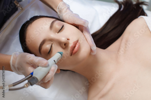 Professional female cosmetologist doing hydrafacial procedure in Cosmetology clinic. photo