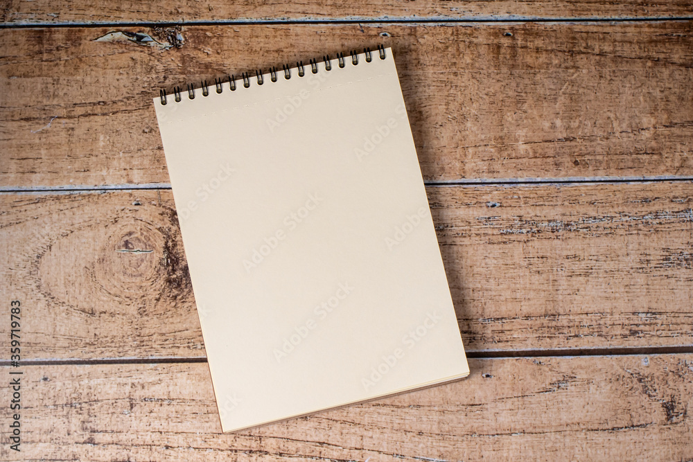 White sheet page notepad on a wooden brown background. A pad on a spiral, a place for notes. White sheet page notepad on a wooden brown background. A pad on a spiral, a place for notes.