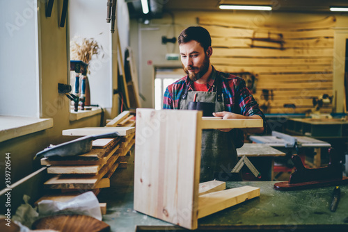 Self employed owner of restoration manufacture creating and repairing wood equipment, experienced man artisan 30s concentrated on improvement decorative handmade chair during working process