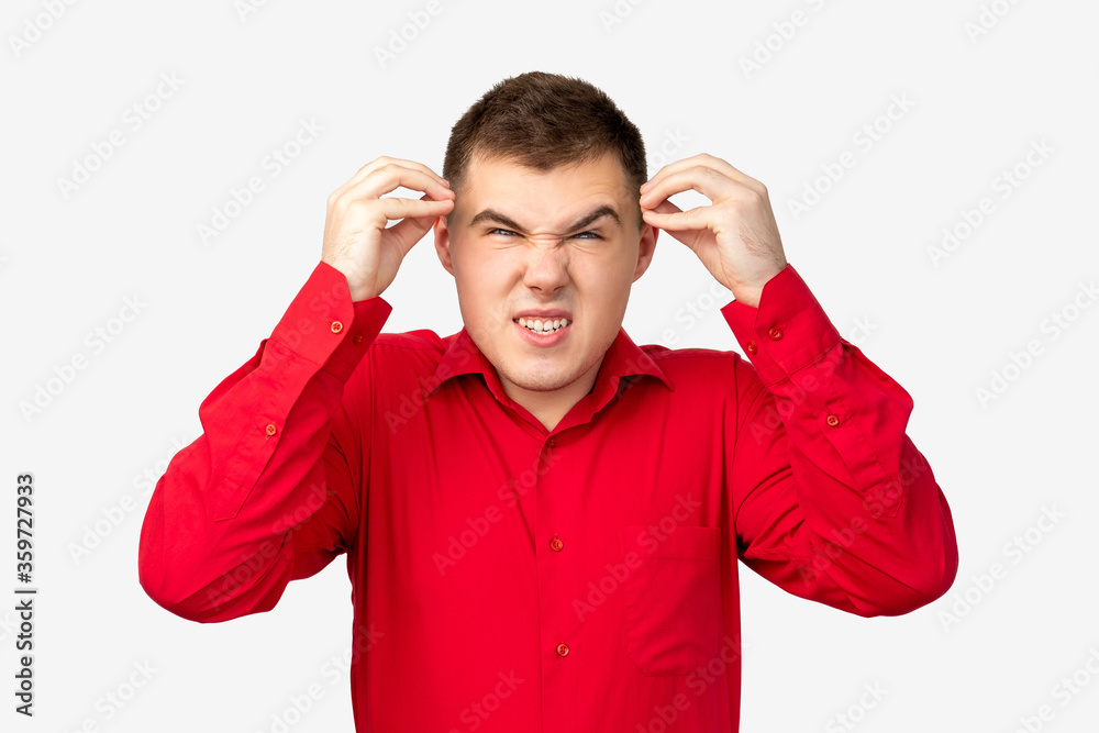 Naklejka premium Frustrated man portrait. Nervous breakdown. Angry guy in red shirt touching head isolated on white background.
