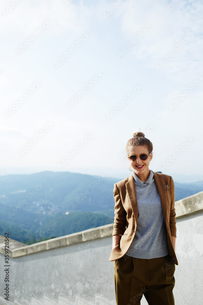 Half length portrait of stylish young woman posing for vacation photo on mountains view background Half length portrait of stylish young woman posing for vacation photo on mountains view background