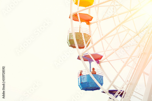 Group of beautiful girls riding on colorful ferris wheel against sunny sky