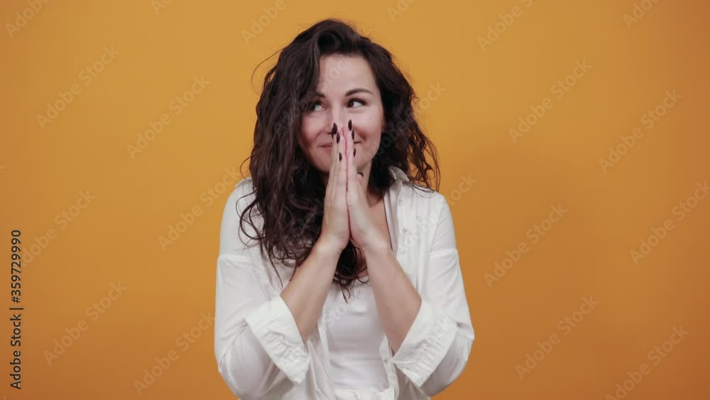 Folded hands together praying asking god for help ask implore wish upwards jesus christ. Young attractive woman, dressed white blouse, with brown eyes, curly hair, yellow background