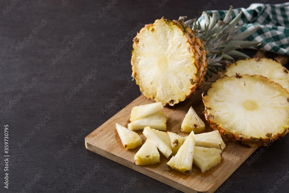 Fresh pineapple slices on cutting board and black stone background. Copy space Fresh pineapple slices on cutting board and black stone background. Copy space