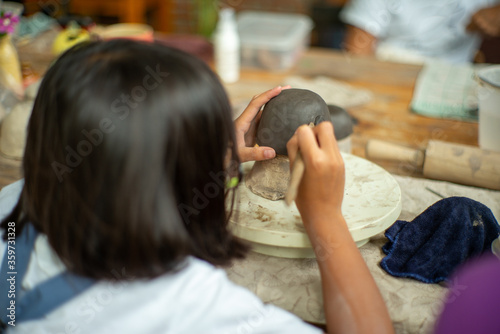 Closeup clay work on the plasted model with motion blurred hands of student laerning in the workshop classroom