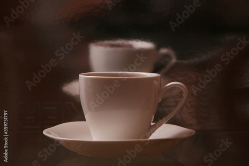 White cup with coffee on a glass table. Background - mirror 3D reflection.