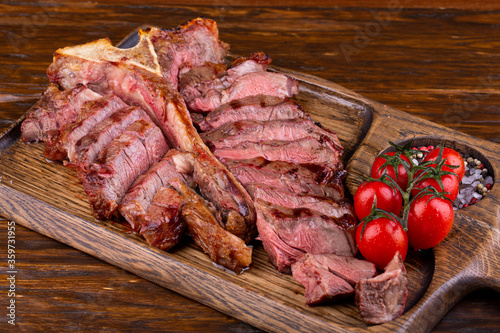Tender lamb meat, fried medium, served on a board with tomatoes