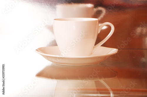 White cup with coffee on a glass table. Background - mirror 3D reflection.