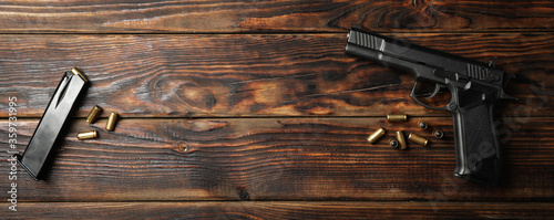 Pistol, bullets and magazine on wooden background