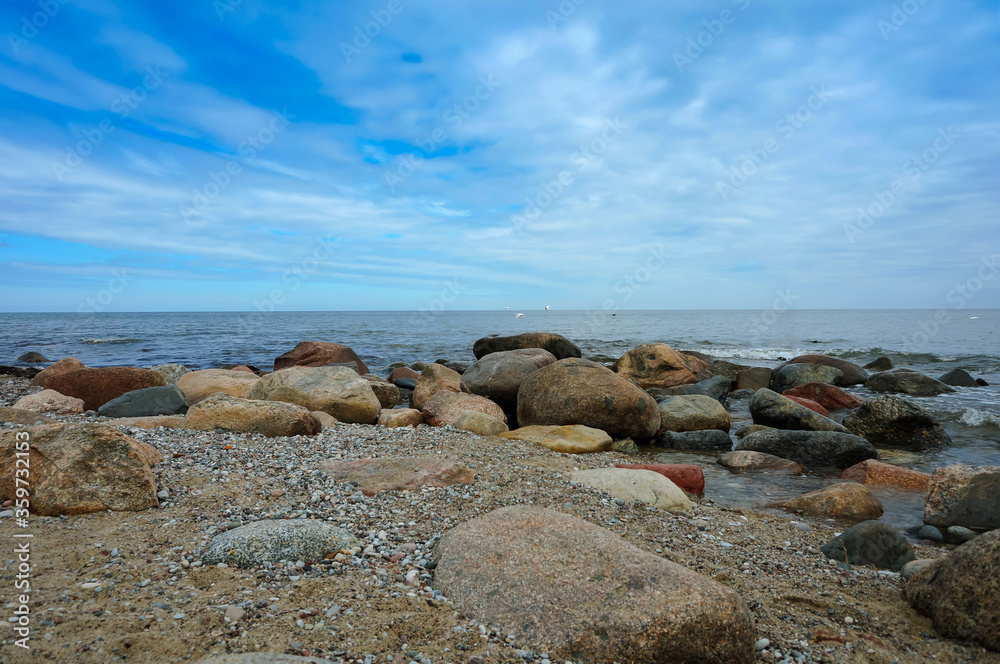 Rocks on the seashore. The sandy shore of the sea. Waves on the Baltic Sea.