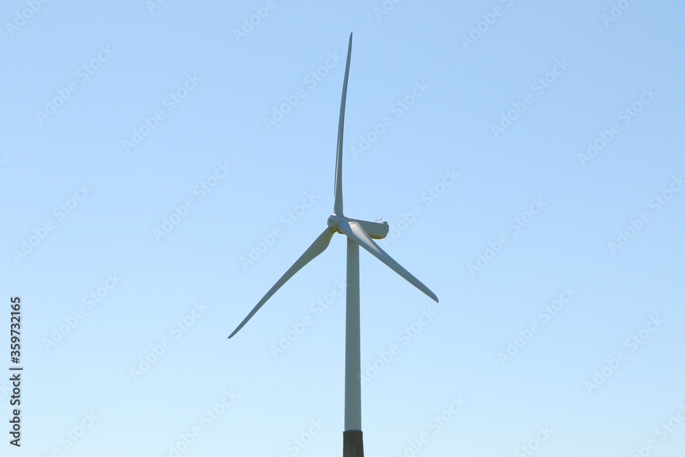 A wind turbine rotates against a blue sky. A wind turbine rotates against a blue sky.