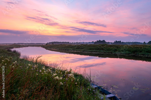 Summer pink sunrise over the river. Calm, relaxing rural landscape.