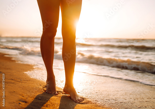 Woman legs walking along the sea coast at sunset. The concept of relax  travel  freedom and summer vacation.