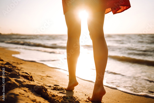 Fototapeta Naklejka Na Ścianę i Meble -  Woman legs walking along the sea coast at sunset. The concept of relax, travel, freedom and summer vacation.