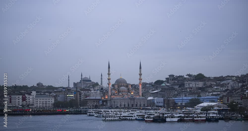 Day to night timelapse in Istanbul, Turkey. Time lapse of New Mosque (Yeni Cami) on the banks of the Golden Horn and Bosphorus River at night with Hagia Sophia (Aya Sofya) behind Day to night timelapse in Istanbul, Turkey. Time lapse of New Mosque (Yeni Cami) on the banks of the Golden Horn and Bosphorus River at night with Hagia Sophia (Aya Sofya) behind