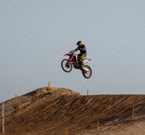 Motorcyclist jumping with his motorcycle in the air captured doing stunt in motocross race.