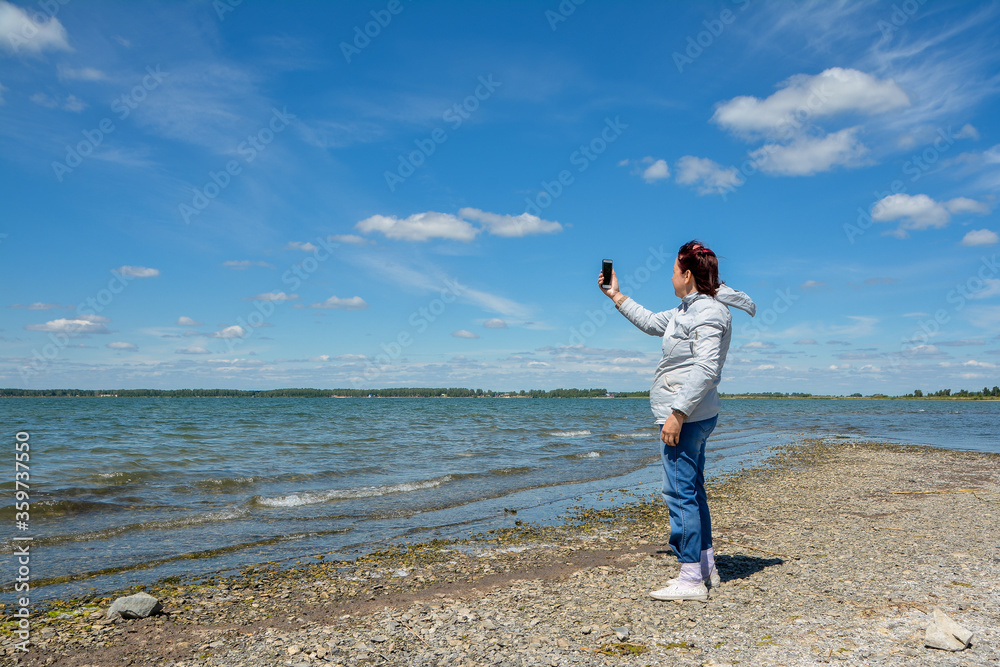 a woman takes photos of a beautiful landscape on her smartphone