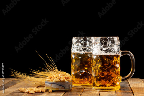 Draft beer in glasses and peanut on wooden surface