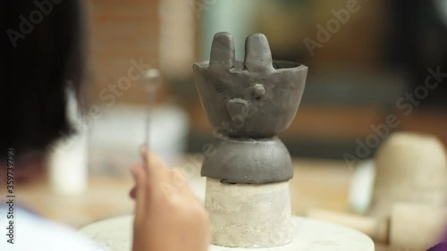 Hands of young girl doing the decoration on the clay pottery in workshop classroom.