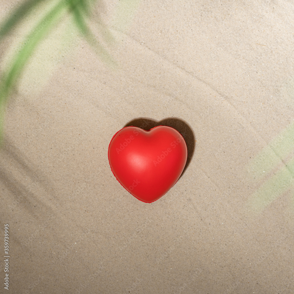 Red heart on sandy tropical beach under branches of palm and shadow palm tree. Valentines day, love. Holiday concept. Creative, background, travel, summer. Red heart on sandy tropical beach under branches of palm and shadow palm tree. Valentines day, love. Holiday concept. Creative, background, travel, summer.