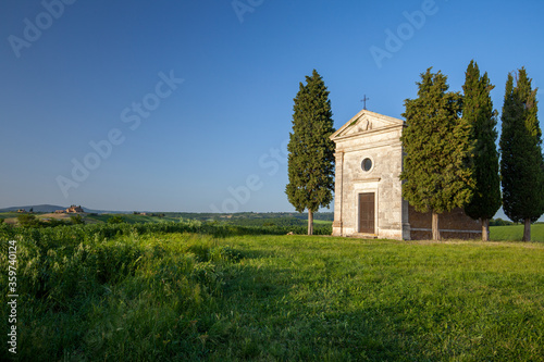 A vertical shot of the famous historic Chapel Vitaleta in the middle of a field in Italy photo