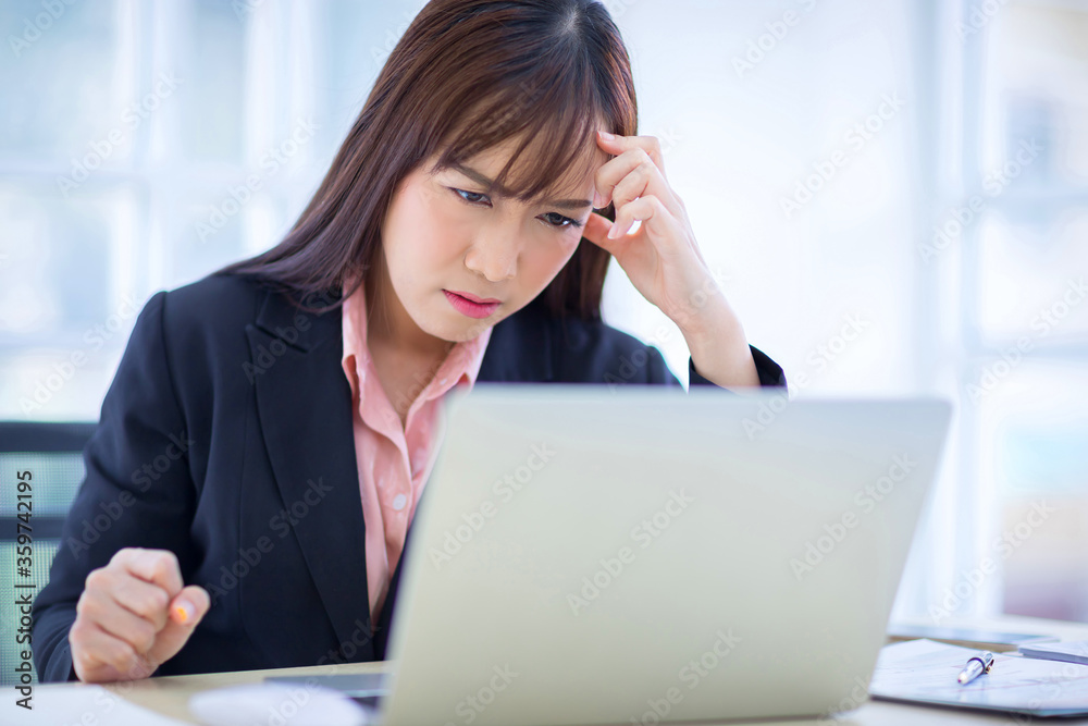 Beautiful Asian women disappointed with the job project. There is a laptop on the table in office. Beautiful Asian women disappointed with the job project. There is a laptop on the table in office.