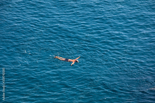 A man swimming alone against the blue Adriatic Sea in Polignano a Mare. Italy