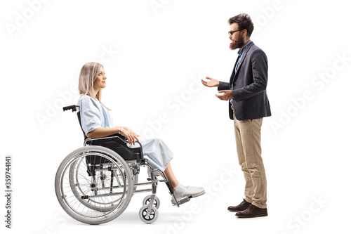 Full length profile shot of a hospitalized female patient in a wheelchair and a bearded man talking