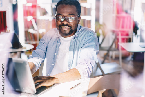 Adult ethnic man using laptop in light contemporary office © BullRun