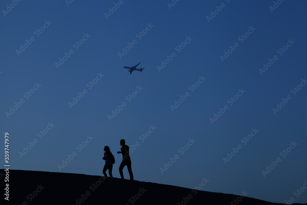 silhouette of family in Dubai desert with airplane flying
