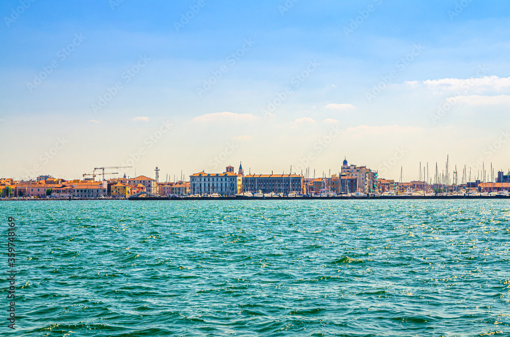 Panoramic view from sea lagoon of Chioggia town cityscape with port and old buildings in historical centre, blue sky background in summer day, Veneto Region, Northern Italy