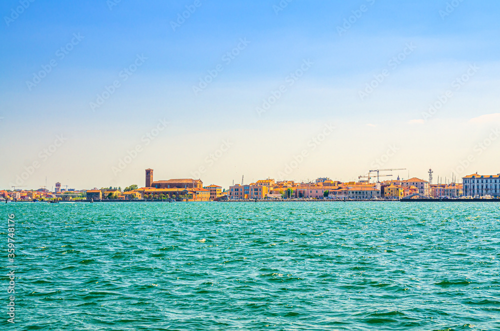 Panoramic view from sea lagoon of Chioggia town cityscape with Saint Domenico catholic church and old buildings in historical centre, blue sky background in summer day, Veneto Region, Northern Italy