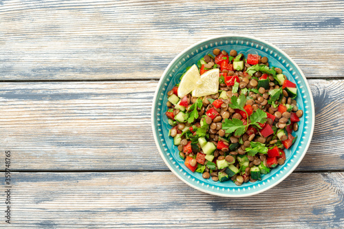 Lentil salad with cucumber, bell pepper and coriander leaves on rustic wooden table