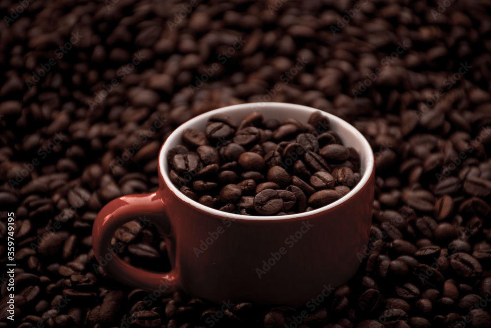 red coffee cup filled and surrounded by black coffee beans red coffee cup filled and surrounded by black coffee beans
