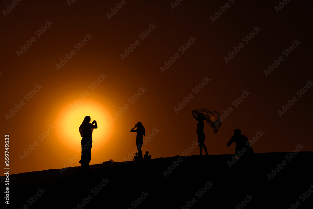 group of people walking on the desert of Dubai at sunset