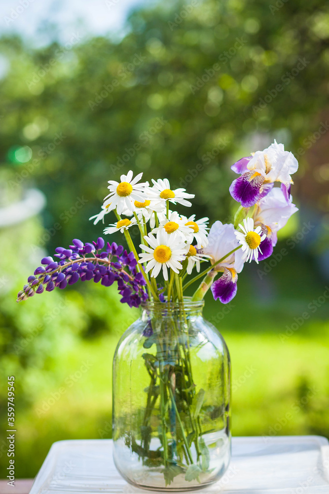 Beautiful bouquet of wild flowers in the light of the setting sun in a glass vase Beautiful bouquet of wild flowers in the light of the setting sun in a glass vase