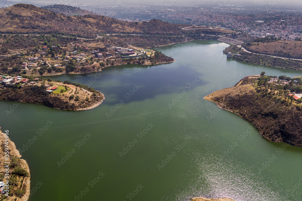 vista aérea de la presa Madin rodeada de zonas áridas, carretera y viviendas, al norte del valle de México