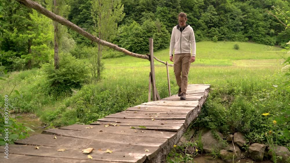 Image of man crossing small wooden bridge at Zumberal national park. Image of man crossing small wooden bridge at Zumberal national park.