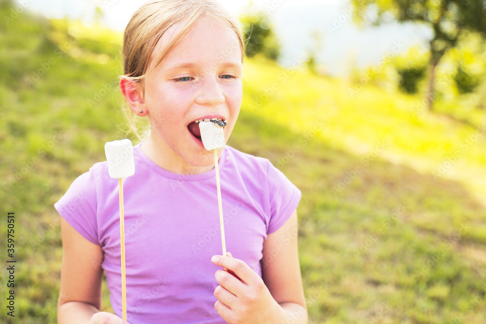 Portrait of blonde cute girl eating roasted marshmallows. Summer camp, vacation. Family time. Selective focus. Portrait of blonde cute girl eating roasted marshmallows. Summer camp, vacation. Family time. Selective focus.
