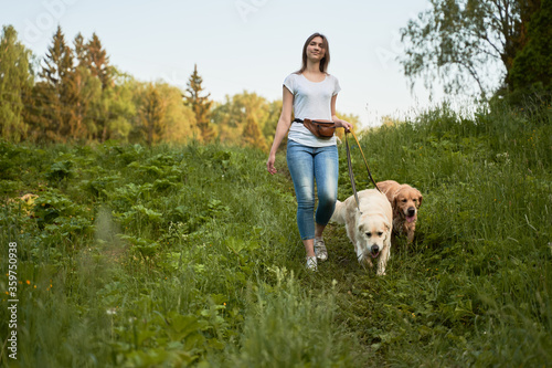 Photography Young woman on walk with two dogs in park on summer