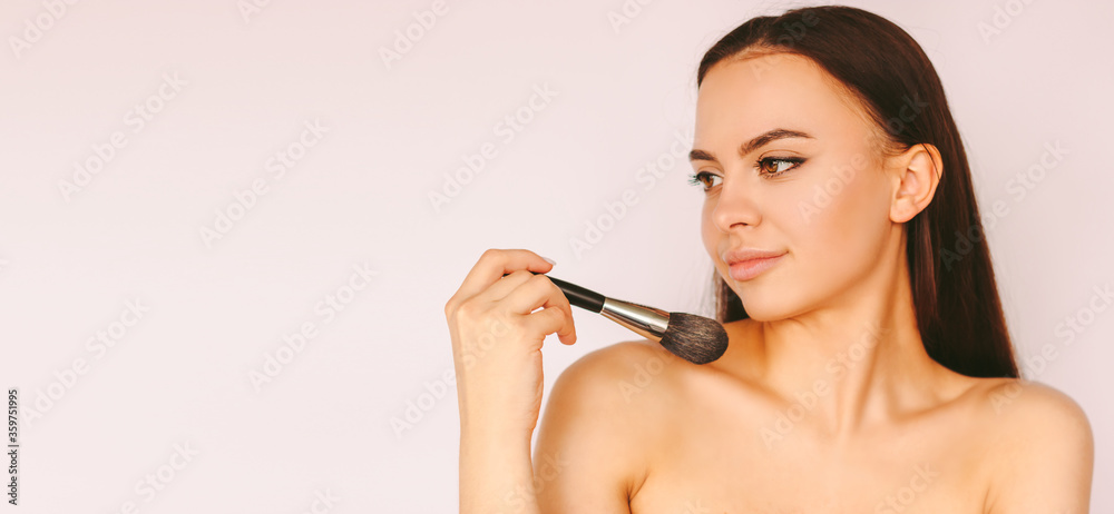 Portrait happy attractive young woman apply foundation powder cream on face and smile isolated white background. Beautiful stylish girl posing with make up brush in hand. Professional make up artist