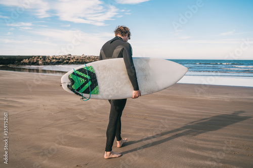 Surfer standing in the ocean with his surfboard.